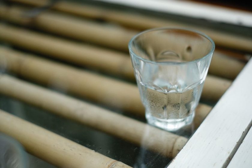 A glass of water on a wooden table beside fresh fruit
